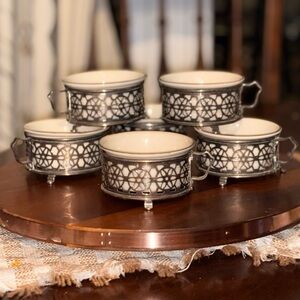 Elegant ceramic custard bowls inside of silver holder with handle and feet